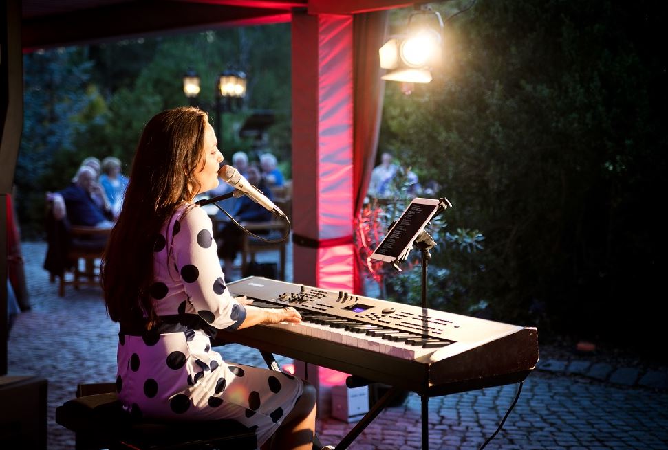 Singer under balcony in golf park at piano