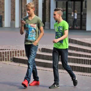 Zwei Jugendliche laufen durch eine Stadt mit Telefon in der Hand