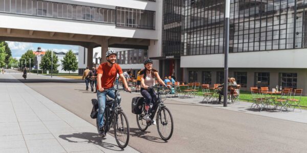 Zwei Radfahrer vor dem Bauhausgebäude Dessau