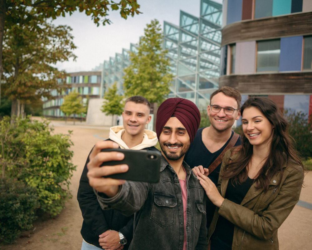Vier Personen machen ein gemeinsames Bild von sich vor dem Bundesumweltamt in Dessau
